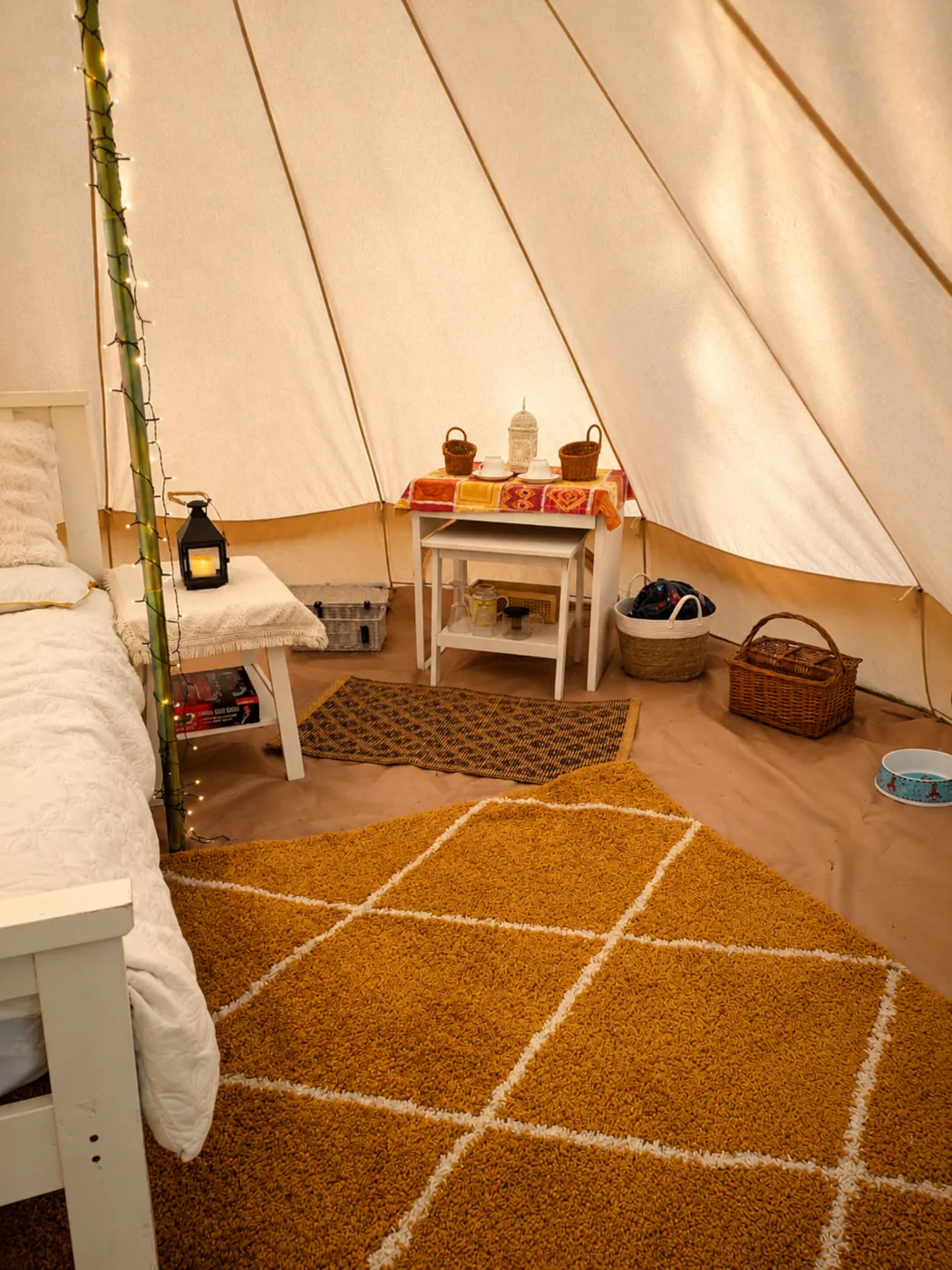 A cosy corner of the Bell Tent with lantern, table and coir matting