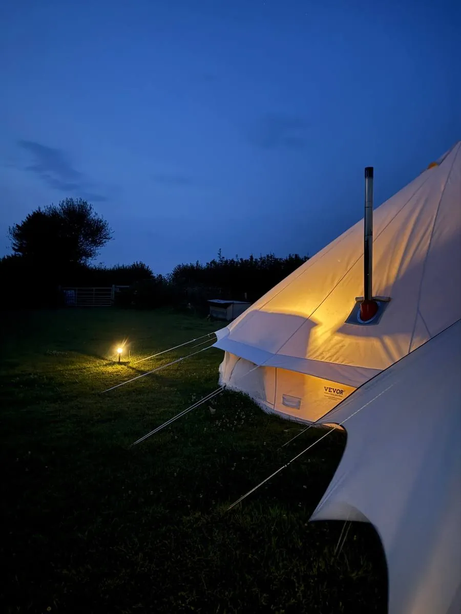 A bell tent glowing warmly against a dark night sky