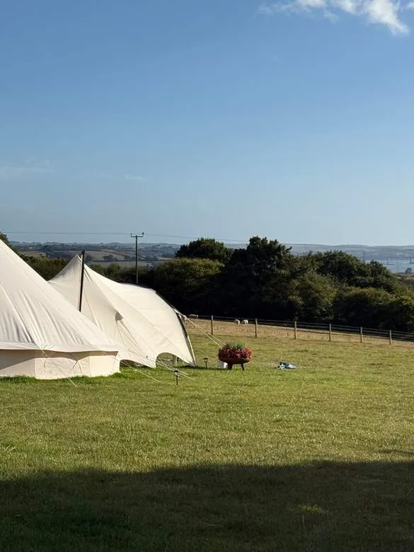 Two bell tents on the hill with the Tamar estuary beyond
