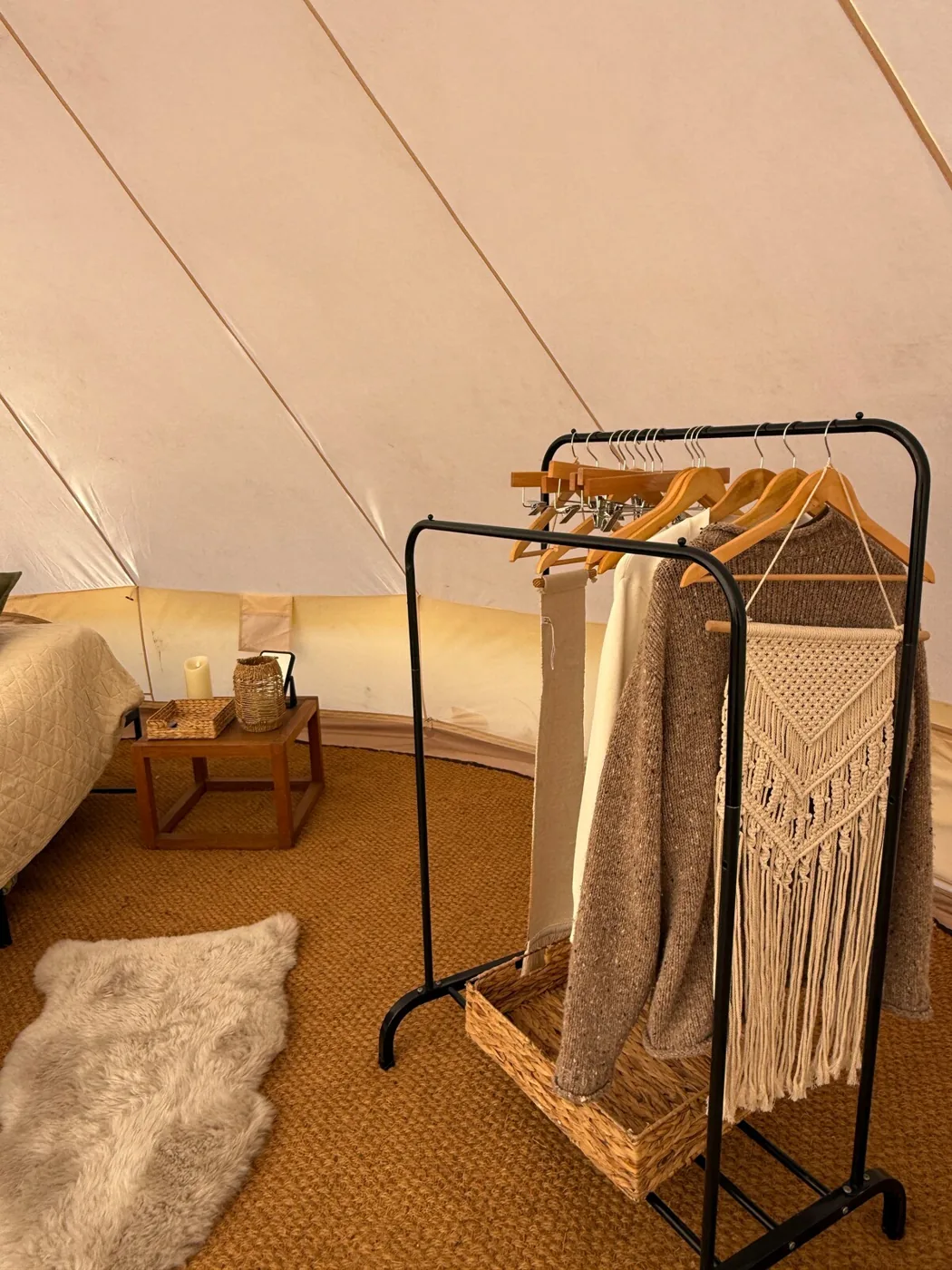 A cosy corner of the Family Tent with a clothes rail and sheepskin rug
