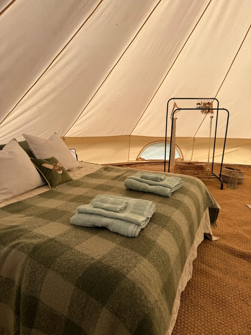 A double bed made up with a green check blanket and fresh towels