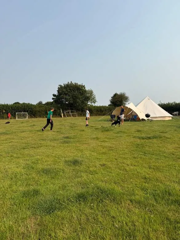 Children playing football on the field beside the tents