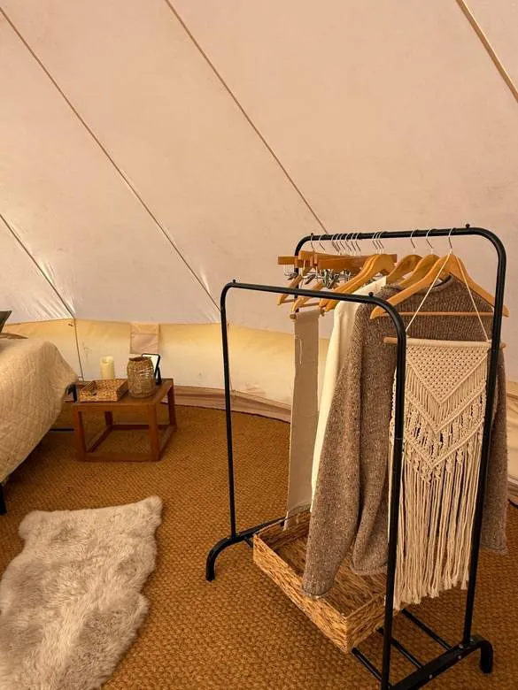 A cosy tent corner with a clothes rail, macramé and a sheepskin rug