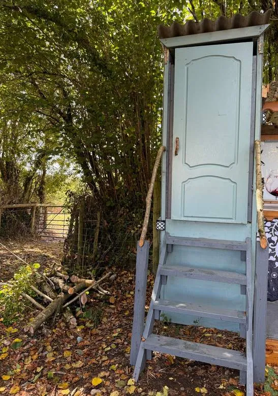 The compost loo with its painted door at the edge of the field